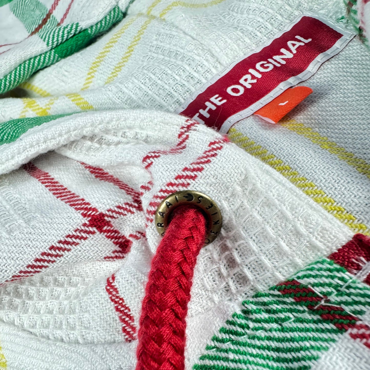 Close-up of the dishcloth fabric out of which a hoodie has been made, featuring a red drawchord and a visible brand tag saying The Original.