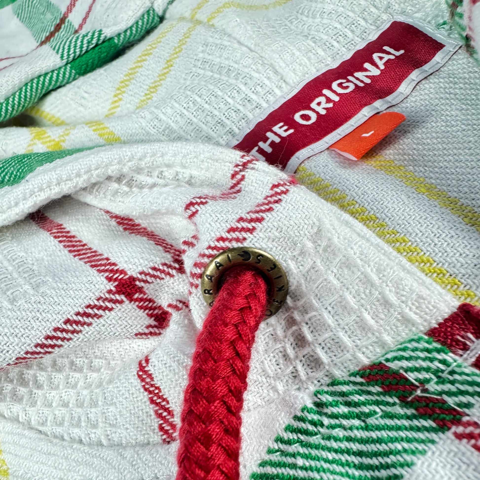 Close-up of the dishcloth fabric out of which a hoodie has been made,  featuring a red drawchord and a visible brand tag saying The Original.